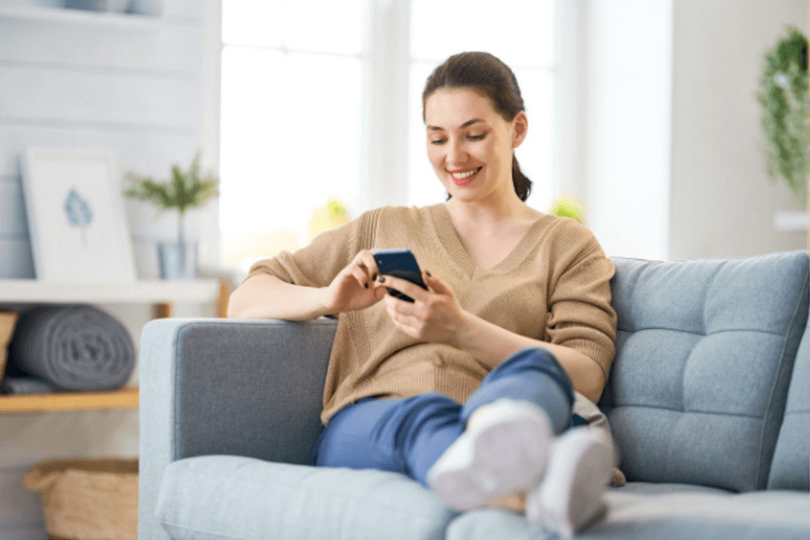 A woman scrolling on her phone on a couch